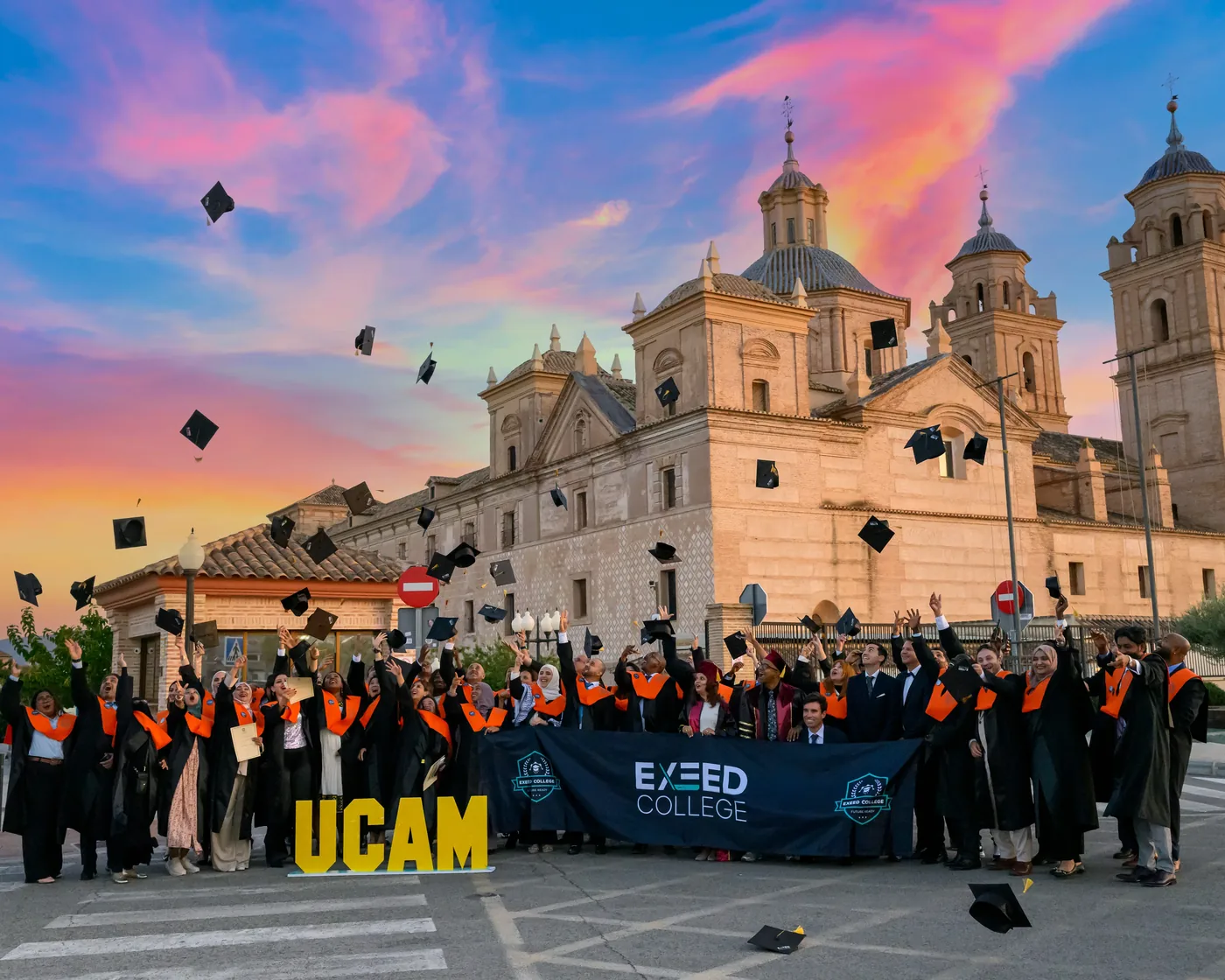 Taito graduates celebrating at sunset outside UCAM